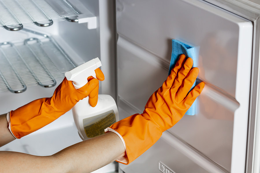 worker in gloves wiping the refrigerator