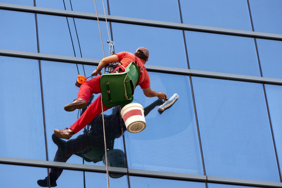 man in a rope cleaning the building window