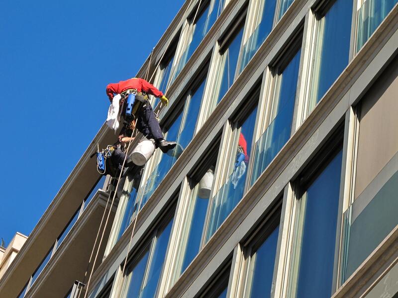 workers in a rope cleaning the windows